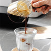 Una mano vierte espresso de una taza medidora en una bebida helada.
