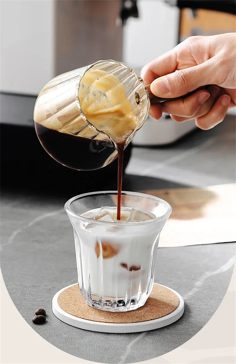Una mano vierte espresso de una taza medidora en una bebida helada.