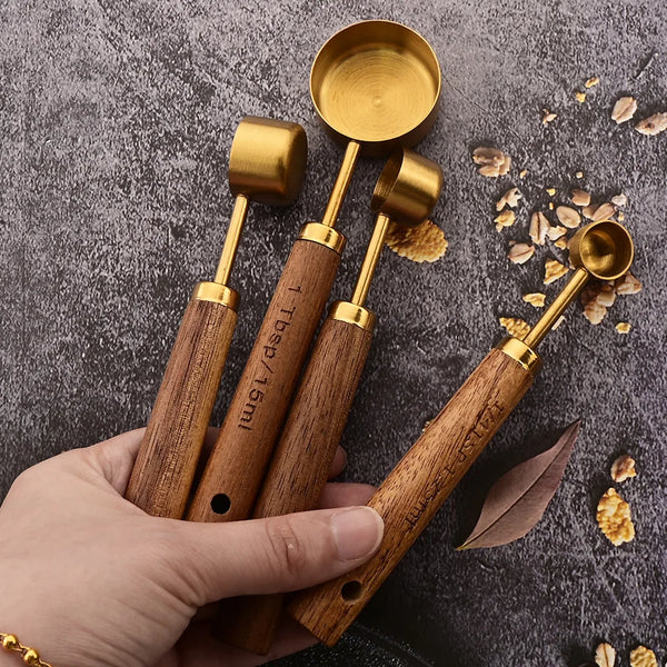 Eine Hand hält ein vierteiliges Edelstahlmessset mit Holzgriffen und goldenen Akzenten auf einer dunklen Oberfläche.