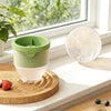 Juego de moldes para bolas de hielo de silicona reutilizables con contenedor verde y blanco y esfera transparente sobre una t