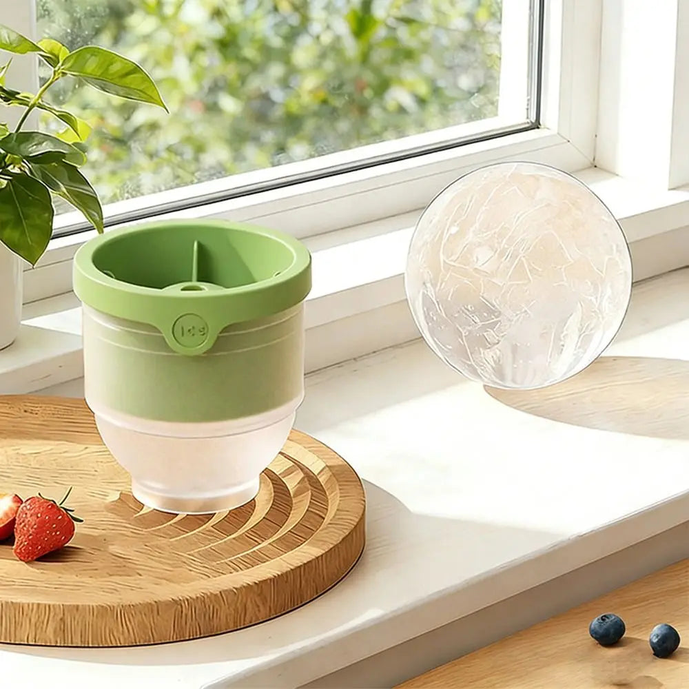 Juego de moldes para bolas de hielo de silicona reutilizables con contenedor verde y blanco y esfera transparente sobre una t