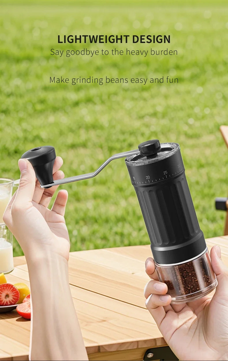 A hand holds a lightweight manual ceramic coffee grinder with an adjustable scale, positioned outdoors on a wooden table.