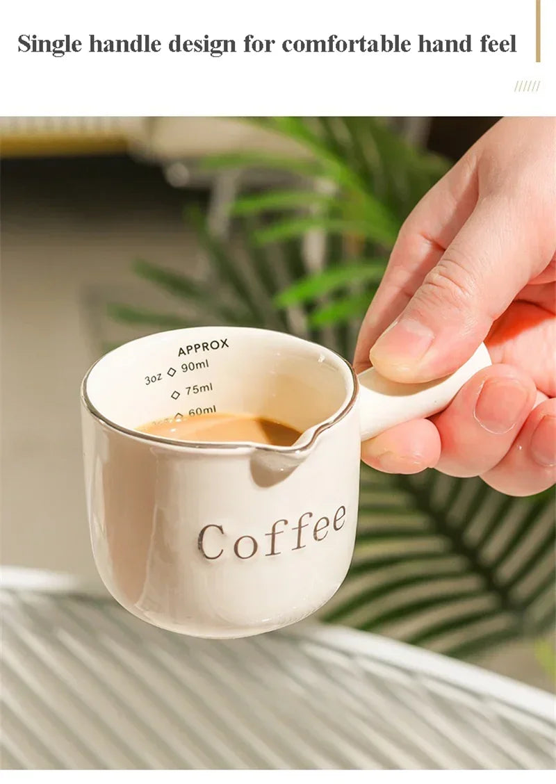 A hand holds a single-handle ceramic coffee cup with a handle, demonstrating its design for a comfortable hand feel.