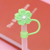 A light green flower straw cap with white petals and stamens is attached to a clear plastic straw.