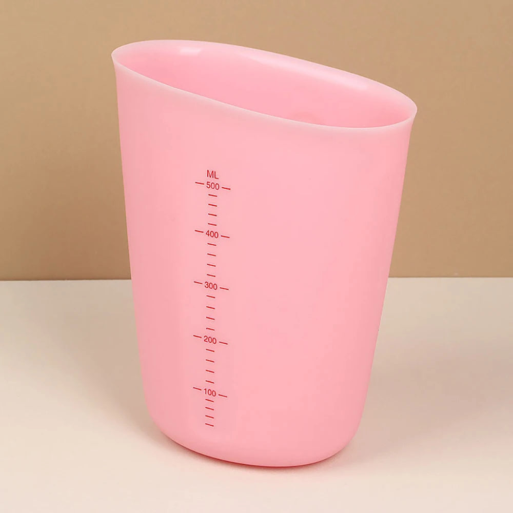 A pink silicone measuring cup with volume markings is shown on a light surface.