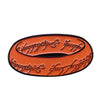 An enamel pin featuring a gold-colored design with black lettering on an orange background.
