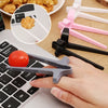A hand holds a gray finger guard chopstick next to a laptop keyboard and several pink and black plastic chopsticks.