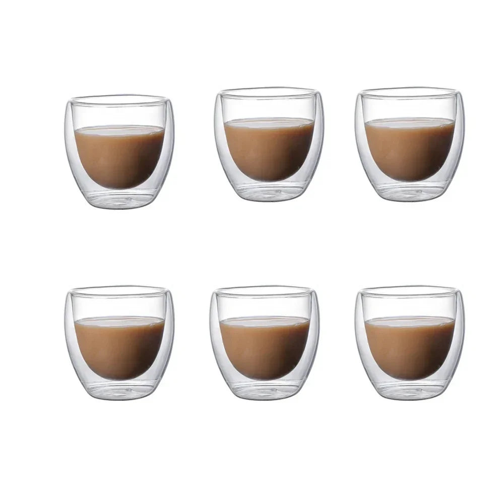 A set of four clear double-walled glass coffee mugs filled with brown liquid.
