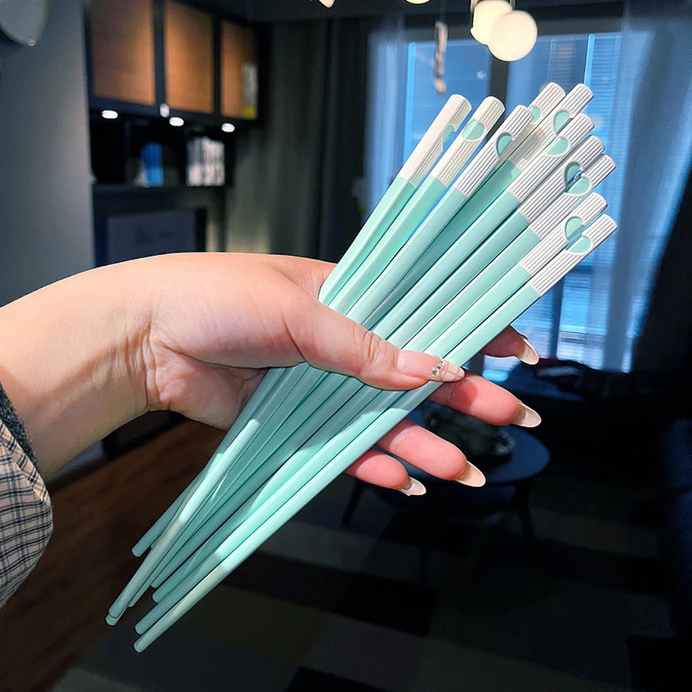 A hand holds a set of reusable Japanese Chinese chopsticks with light blue and white tips.