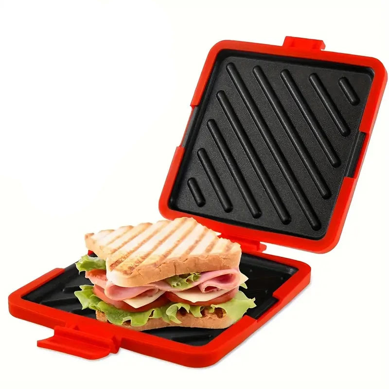An orange silicone sandwich maker with a black grill plate containing a sandwich.