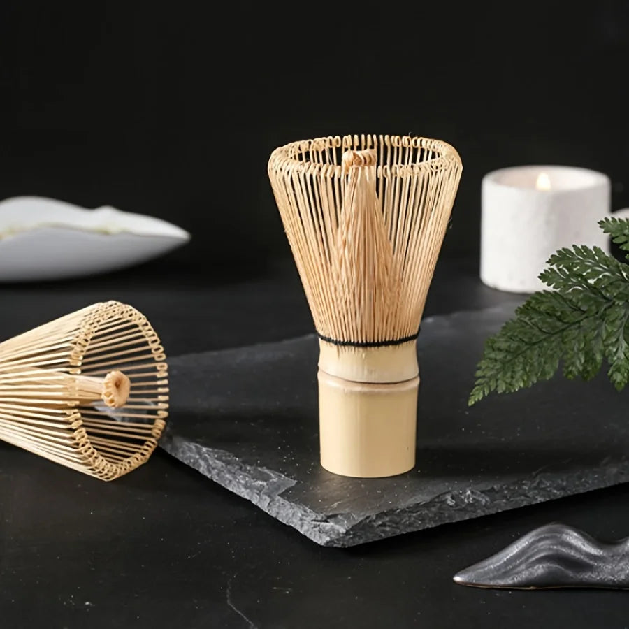 A set of natural bamboo tea tools, including a funnel-shaped item and a round sieve, displayed on a dark surface.
