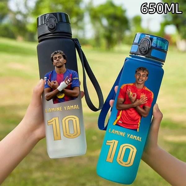A hand holds a 650ml Lamine Yamal football star water bottle with a flip cover, featuring a player graphic.