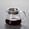 A clear glass manual pour over coffee dripper filled with dark brewed coffee.