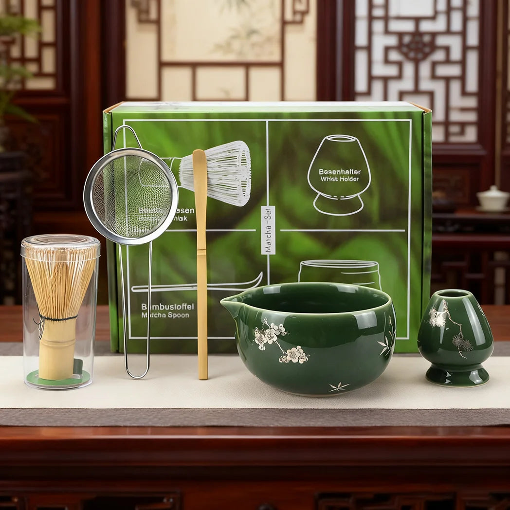 A green box containing a matcha whisk set, including a bamboo whisk and a bowl, is displayed on a wooden table.