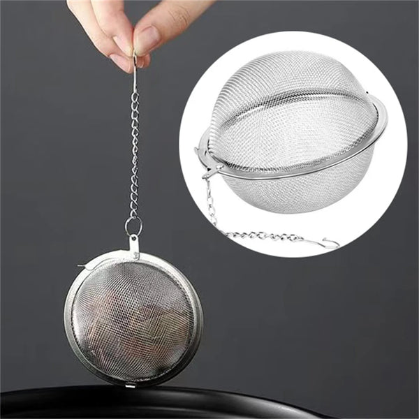 Edelstahl-Tee-Infuserkugel mit Maschenhaube, gehalten in der Hand und vor dunklem Hintergrund