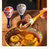 A wooden spoon holds soup from a colorful ceramic bowl filled with yellow and brown ingredients.
