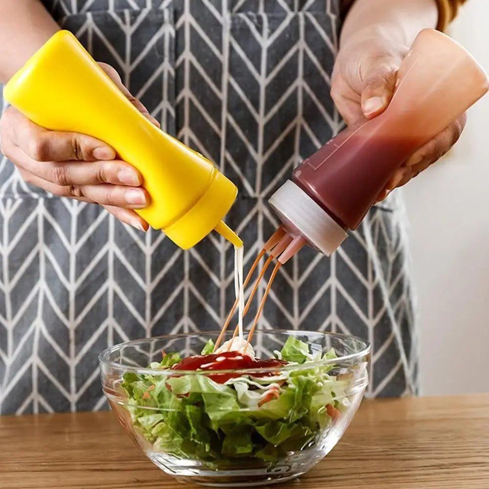 Hands squeezing a yellow bottle of dressing onto a green salad in a glass bowl.