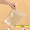A hand is pressing a sliding seal onto a plastic bag to make it watertight for food preservation.