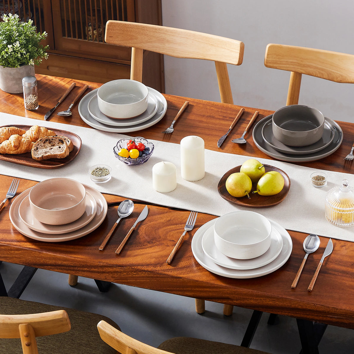 A wooden table set featuring a sesame glaze stoneware dinnerware collection with plates, bowls, and cutlery.