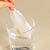 A hand is lifting a white reusable fine mesh food strainer colander filled with water.