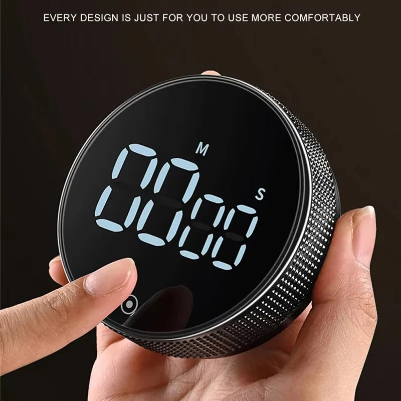 A hand holds a black magnetic kitchen timer with a digital display showing 00:00.