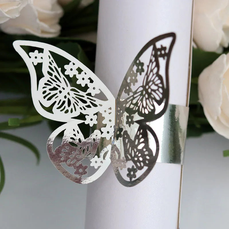 A pair of laser cut butterfly napkin rings in silver and dark brown shades attached to a white cylindrical object.
