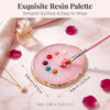 A pink resin palette with various colored dots and a brush set for nail art is displayed on a marble surface.