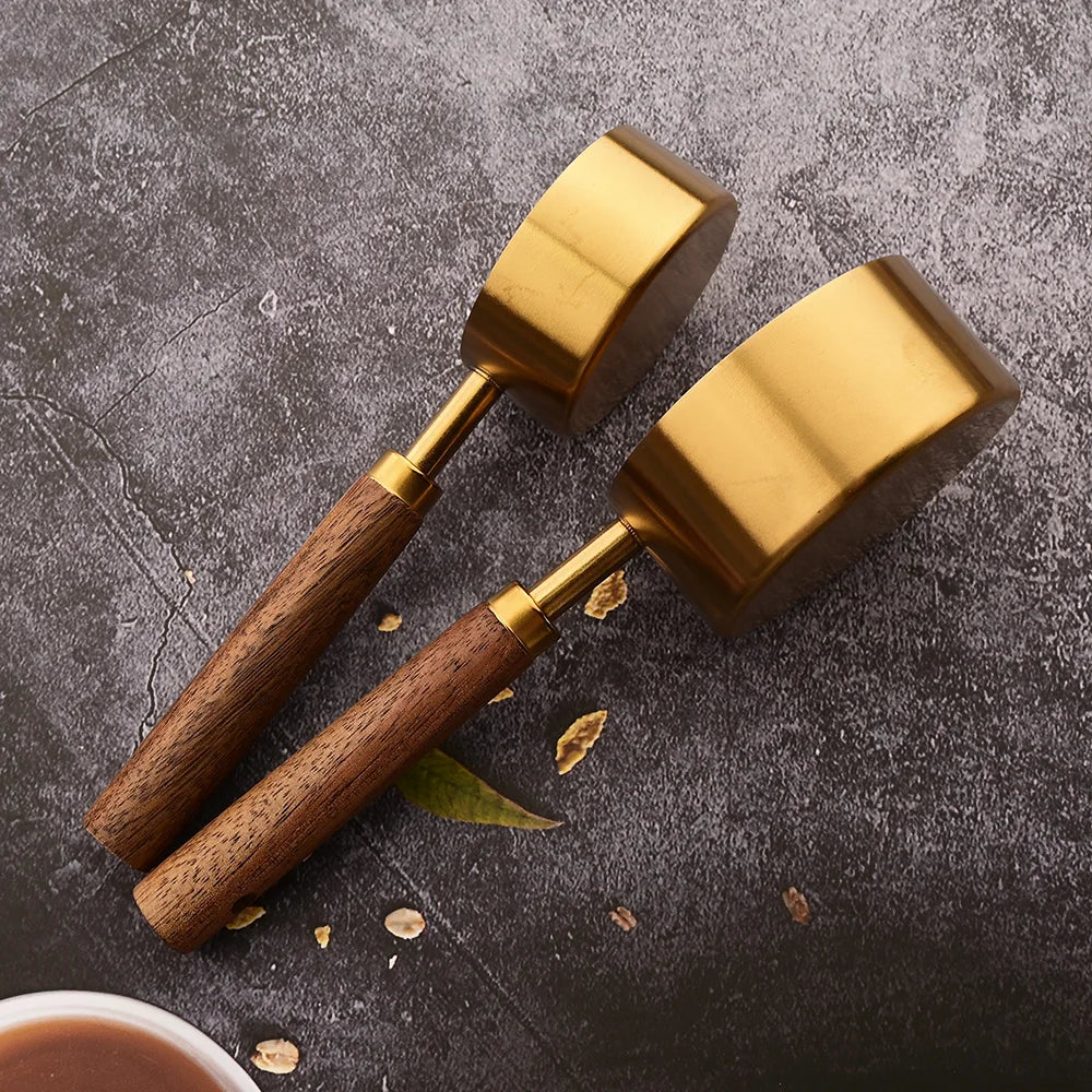 A pair of brass and wood measuring spoons resting on a dark surface.