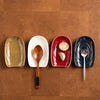A row of four vintage ceramic spoons and bowls in earthy tones arranged on a wooden surface.