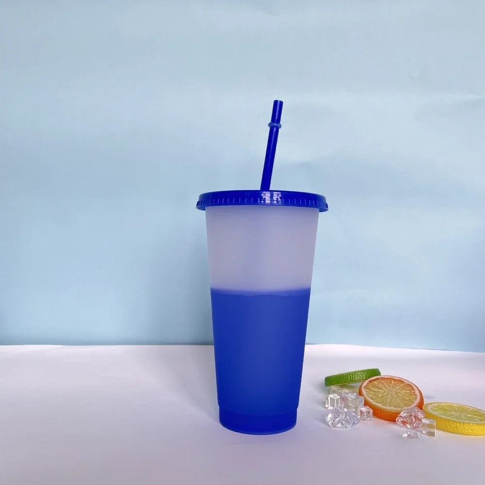 A blue plastic tumbler with a blue straw sits on a white surface next to citrus slices.