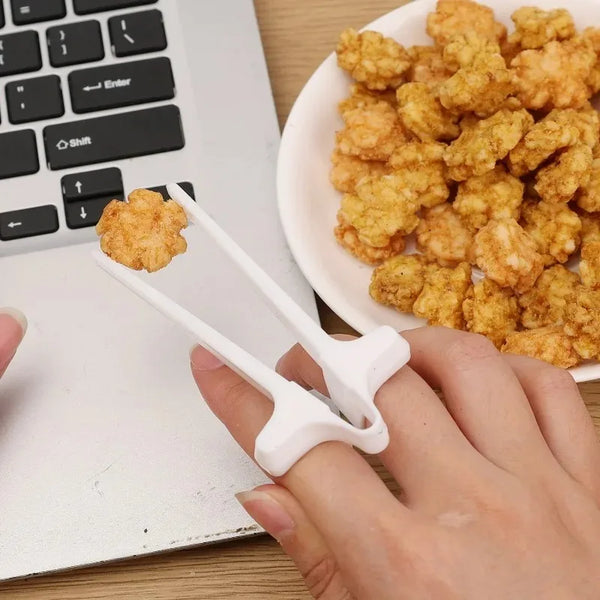 Eine Hand hält weiße Finger-Stäbchen mit frischem Essen auf einem Holzschreibtisch neben einem Laptop.