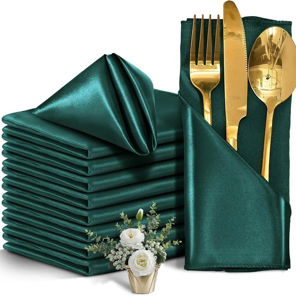 A stack of ten emerald green satin dinner napkins next to a set of gold silverware.