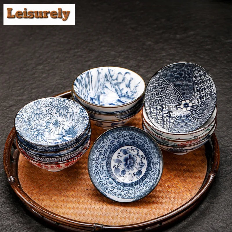 A set of handmade blue and white porcelain cups and bowls displayed on a woven tray.